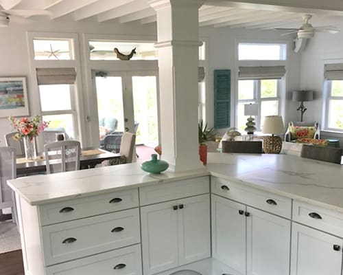 A kitchen with white cabinets and a table in the center.