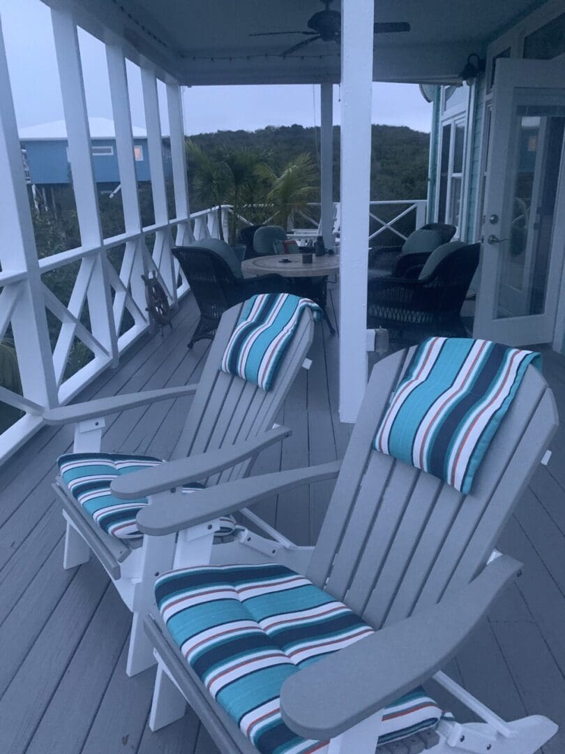 A deck with chairs and a view of the ocean.